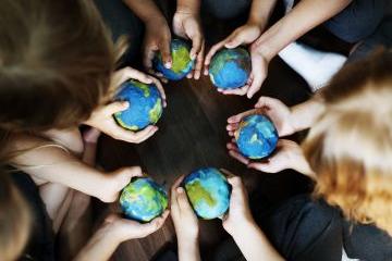 Childrens hands reaching towards the Earth