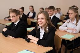 Girls sat at desk with arms folded in front of a row of orderly students